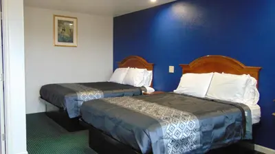 two beds in a hotel room with blue walls at Corcoran Country Inn in Corcoran