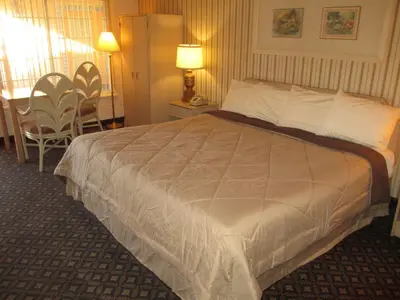 a bedroom with a large white bed with two chairs at Victorian Inn in Reno