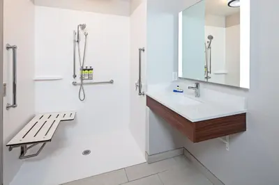 a bathroom with a sink and a mirror and a bench at Holiday Inn Express & Suites Clovis Fresno Area by IHG in Clovis