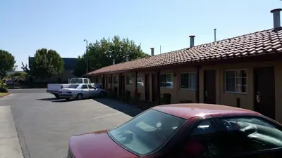 a red car parked in a parking lot next to a building at Slumber Motel in Merced
