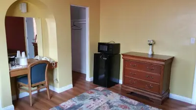 a room with a desk and a refrigerator and a table at Slumber Motel in Merced