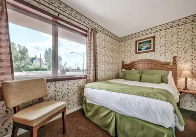 a bedroom with a bed and a chair and a window at Walker River Lodge in Bridgeport