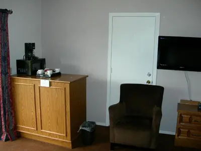 a room with a chair and a desk and a television at Walker River Lodge in Bridgeport