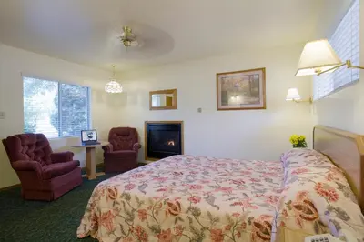 a bedroom with a bed and two chairs and a fireplace at Lazy J Ranch Motel in Three Rivers