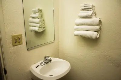 a bathroom with a sink and a mirror and towels at King's Rest Motel in Gilroy