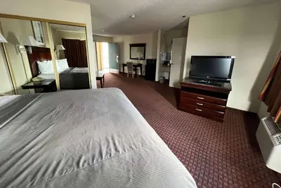a hotel room with a bed and a flat screen tv at Days Inn & Suites by Wyndham Rancho Cordova in Rancho Cordova