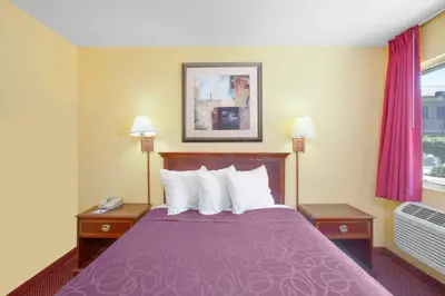a hotel room with a purple bed with two tables at Baymont by Wyndham Coalinga in Coalinga