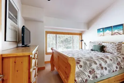 a bedroom with a bed and a tv and a window at Tavern Inn #55 in Olympic Valley