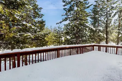 a deck covered in snow with trees in the background at Inviting, Comfortable Mountain Home in Truckee