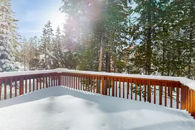 a deck covered in snow with the sun in the background at Inviting, Comfortable Mountain Home in Truckee