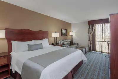 a hotel room with a large bed and a chair at Wyndham Visalia in Visalia