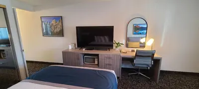 a bedroom with a desk with a television and a bed at Dow Villa Motel in Lone Pine
