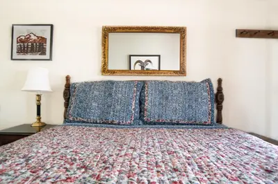 a bedroom with a bed with blue pillows and a mirror at Mt Williamson Motel and Basecamp in Independence