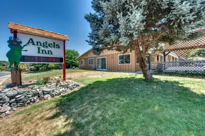 a sign in front of a building with a tree at Angels Inn in Angels Camp