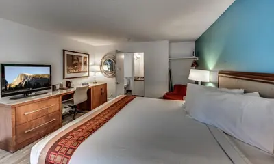 a hotel room with a large bed and a flat screen tv at Angels Inn in Angels Camp