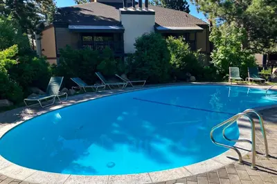 a large blue swimming pool with chairs in front of a house at Sherwin Villas 39 in Mammoth Lakes