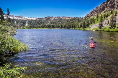 a person is standing on a paddle board in a river at Sherwin Villas 39 in Mammoth Lakes