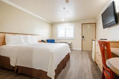a hotel room with a bed and a flat screen tv at Budget Inn Corcoran Near Tulare CA 43 in Corcoran