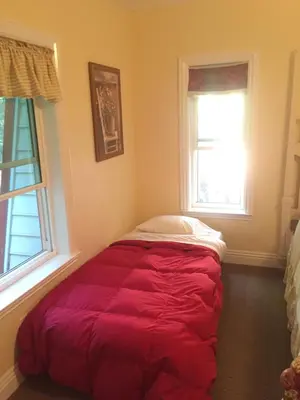 a red bed in a room with two windows at Carriage House at Yosemite in Fish Camp