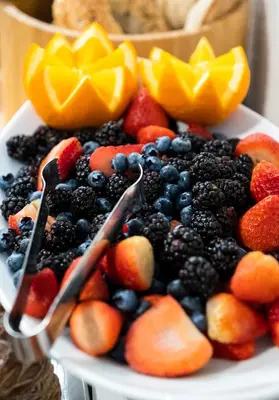 a plate of berries and fruit on a table at Hounds Tooth Inn in Oakhurst