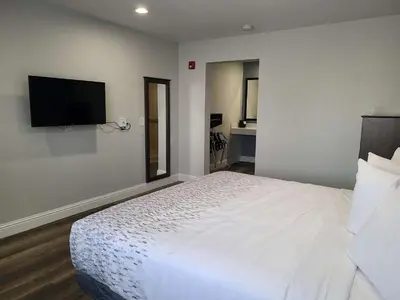 a bedroom with a white bed and a flat screen tv at SureStay Hotel by Best Western Chowchilla Yosemite in Chowchilla
