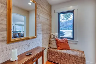 a mirror and a chair in a room with a window at Lake Front Family Home at Donner in Truckee