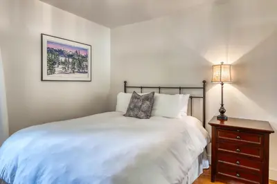 a bedroom with a bed and a nightstand with a lamp at Lake Front Family Home at Donner in Truckee