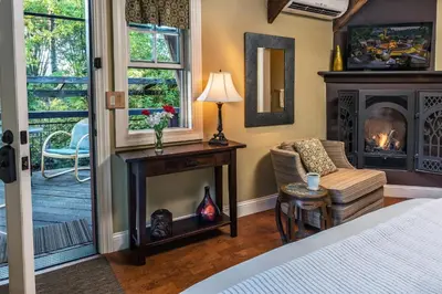 a bedroom with a fireplace and a chair and a bed at Eden Vale Inn in Placerville