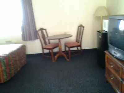 a hotel room with a table and chairs and a television at Budget Inn in Tulare