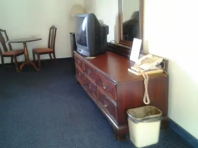 a room with a tv on a dresser with a telephone at Budget Inn in Tulare