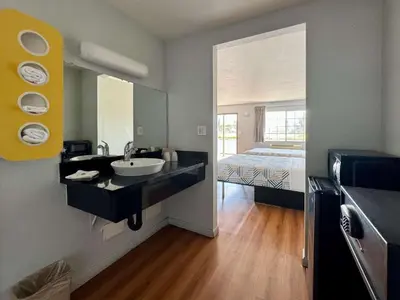 a bathroom with a sink and a bed in a room at Motel 6-Delano, CA in Delano