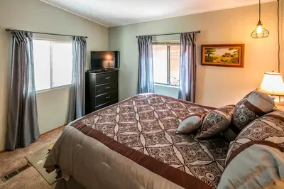 a bedroom with a bed with pillows and a television at Yosemite Cabin in Wawona
