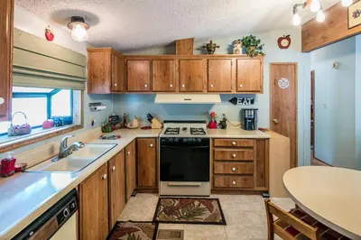 a kitchen with wooden cabinets and a stove top oven at Yosemite Cabin in Wawona