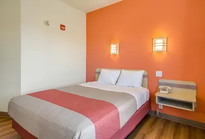 a bed in a room with an orange wall at Howard Johnson by Wyndham Lemoore in Lemoore
