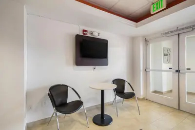 a room with three chairs and a table and a tv at Howard Johnson by Wyndham Lemoore in Lemoore