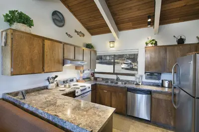 a kitchen with wooden cabinets and a stainless steel refrigerator at Mammoth Point by 101 Great Escapes in Mammoth Lakes