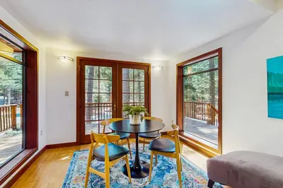 a living room with a table and chairs and windows at Tahoe Donner Tree House Retreat in Truckee