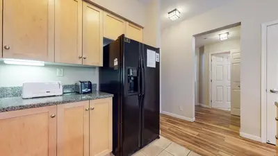 a kitchen with a black refrigerator and wooden cabinets at Mammoth Green #120 Condo in Mammoth Lakes