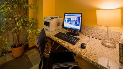 a desk with a computer monitor and a keyboard and mouse at Best Western Palm Court Inn in Modesto