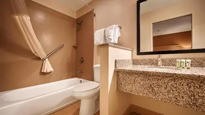 a bathroom with a sink and a toilet and a mirror at Best Western Palm Court Inn in Modesto