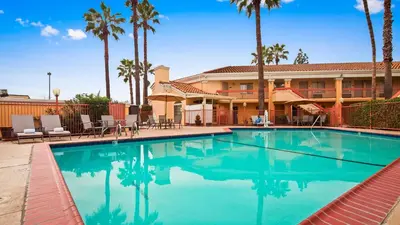 a swimming pool in front of a hotel with palm trees at Best Western Palm Court Inn in Modesto
