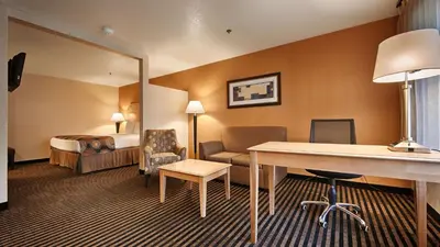 a hotel room with a bed and a desk and chair at Best Western Palm Court Inn in Modesto