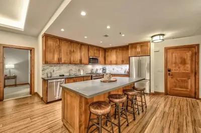 a kitchen with wooden cabinets and a island with bar stools at Steps From Heavenly Village & Gondola-Luxury 3Br Residence Condo in South Lake Tahoe