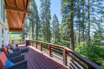 a deck with a couch and chairs on a house at Yosemite Cub's Cabin in Yosemite West