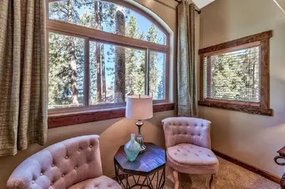 a living room with two chairs and a table and windows at Lv12: luxury villa walk to the Beach in Glenbrook