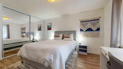 a white bedroom with a large bed and a mirror at Chateau De Montagne #6 Condo in Mammoth Lakes