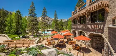 an outdoor patio with tables and umbrellas and a building at Everline Resort and Spa, Lake Tahoe in Olympic Valley