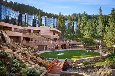 a building with a green yard in front of a mountain at Everline Resort and Spa, Lake Tahoe in Olympic Valley