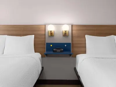 two beds in a room with two lamps on the wall at Microtel Inn & Suites by Wyndham Tracy in Tracy