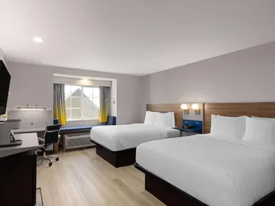 a hotel room with two beds and a desk at Microtel Inn & Suites by Wyndham Tracy in Tracy